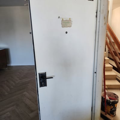 דלת פתוחה עם ידית ומברשת צבע על הרצפה