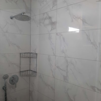 מקלחת עם אריחים חדשים ומדף מתכת