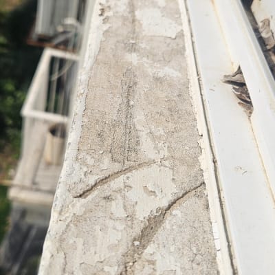 חלון עם מסגרת מתכתית וסדקים בקיר לידו