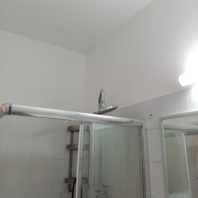 מקלחת עם אריחים לבנים וראש מקלחת כסוף