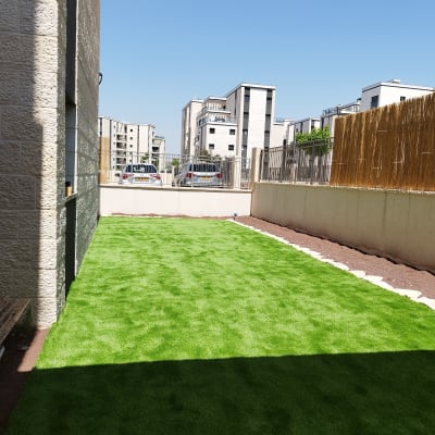 דשא סינתטי בחצר עם שביל אבנים בצד
