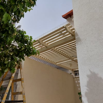 פרגולה מעץ עם סולם ליד קיר חיצוני