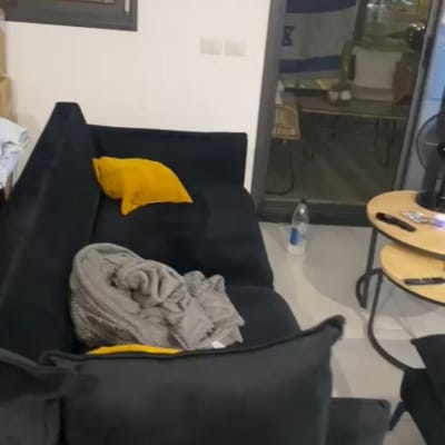 ספה עם כריות ושמיכה, בקבוק מים על הרצפה