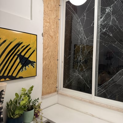 חלון שבור עם לוח עץ וצמחים על מדף