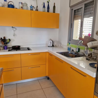 מטבח עם ארונות כתומים, כיור, כיריים וכלים על השיש