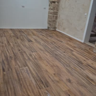 רצפת פרקט בחדר עם קירות אבן ותאורה