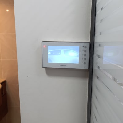 מסך אינטרקום עם תצוגת מצלמה על קיר לבן