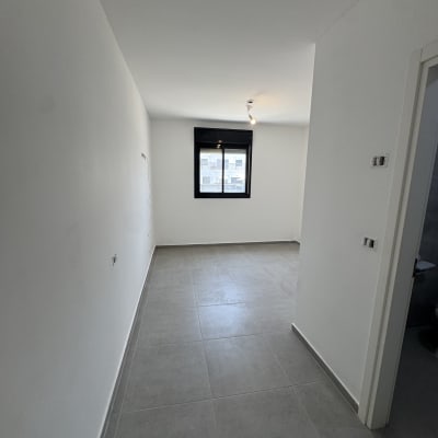 חדר ריק עם קירות לבנים ורצפת אריחים אפורה