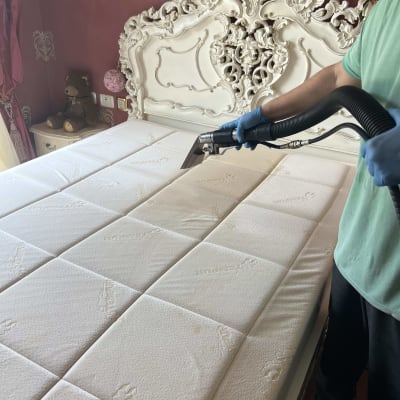 ניקוי מזרן עם שואב אבק על מיטה מעוצבת בחדר שינה.