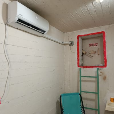 מזגן מותקן על קיר בחדר עם סולם וכיור