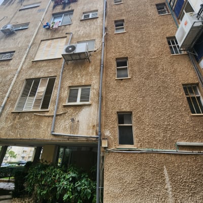 בניין עם מזגנים וצינורות חיצוניים על הקיר