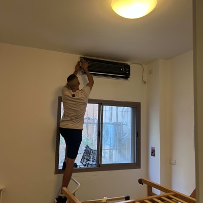 טכנאי מיזוג אוויר מבצע עבודת תיקון במזגן עילי