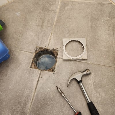 פתח ניקוז פתוח עם פטיש ומברג על הרצפה