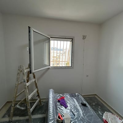 חדר צבוע עם סולם, דלי צבע וכלי עבודה.