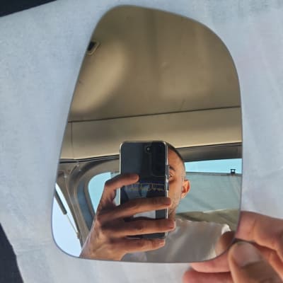 מראה לרכב מוחזקת ביד על רקע רכב