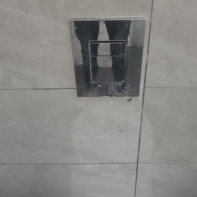 לחצן הדחה על קיר אריחים בשירותים