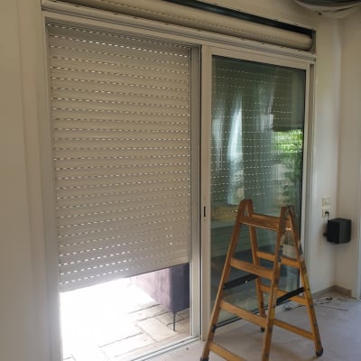 תריסים לבנים חצי פתוחים ליד דלת זכוכית