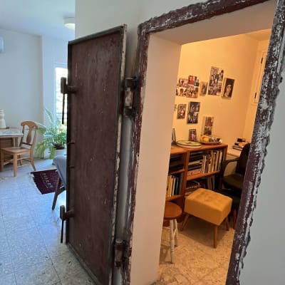 דלת מתכת פתוחה לחדר עם מדפים ותמונות על הקיר