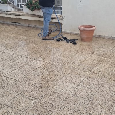 אדם עובד עם צינור מים על גג רטוב