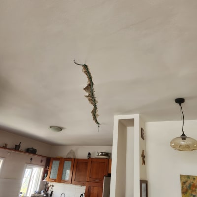 חוטי חשמל חשופים בתקרה עם טיח מתקלף