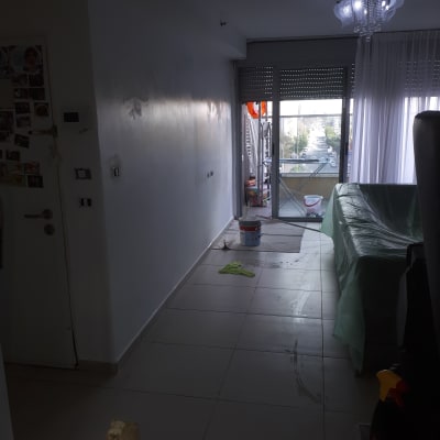 קיר צבוע חלקית עם דלי צבע ומטלית על הרצפה