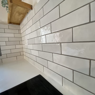 קיר אריחים לבנים במטבח עם מדף עץ