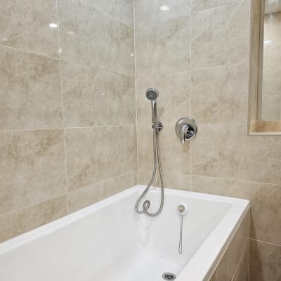 אמבטיה חדשה עם אריחים, ברז ומקלחת יד