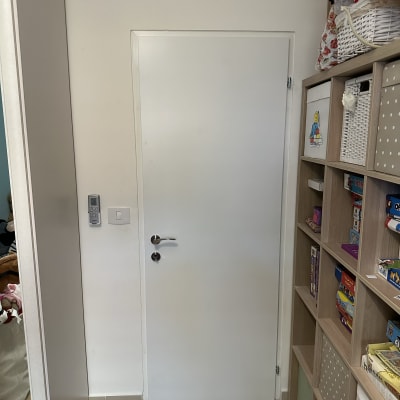 דלת לבנה עם ידית כסופה וקודן על הקיר