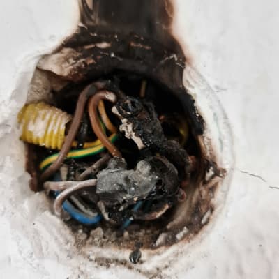 חוטי חשמל שרופים בקיר עם סימני פיח