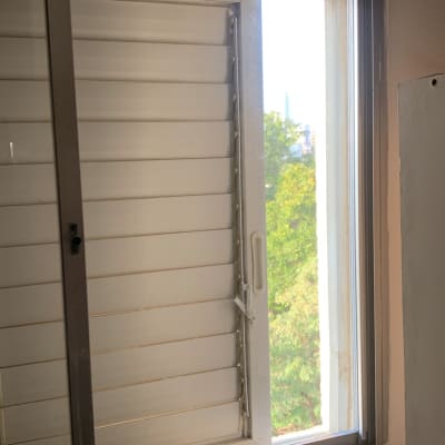 חלון זכוכית פתוח עם תריסים לבנים