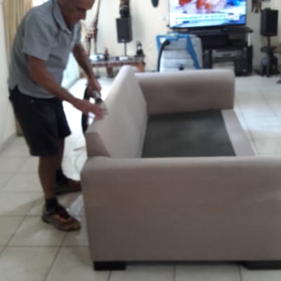 אדם מנקה ספה עם מכשיר ניקוי חשמלי