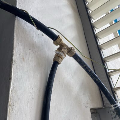 צינור שחור עם מחבר מתכת על קיר לבן