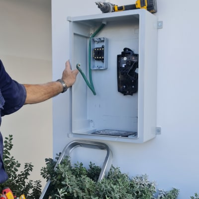 חשמלאי עובד על לוח חשמל עם מקדחה וכלים