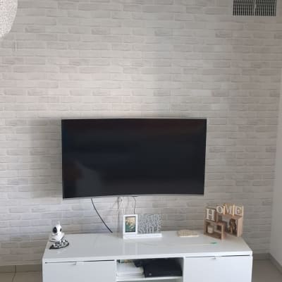 קיר לבנים לבן מאחורי טלוויזיה תלויה