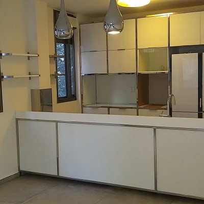 מטבח נקי עם משטחי עבודה לבנים וברז נירוסטה