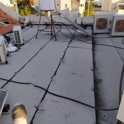 גג עם איטום זפת שחור סביב צינורות ומזגנים