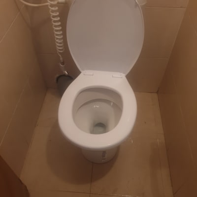 אסלה פתוחה עם צינור מים גמיש ליד