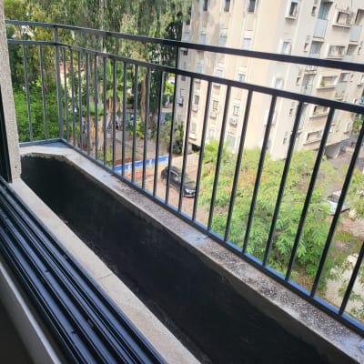 מעקה מתכת שחור במרפסת עם אדנית ריקה