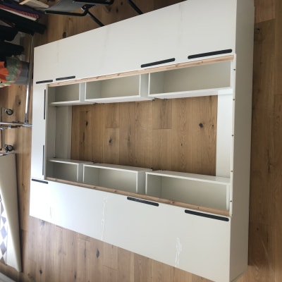 חלקי רהיט לבן מונחים על רצפת עץ להרכבה