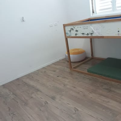 מיטה מוגבהת עם מזרן ירוק וכרית כתומה