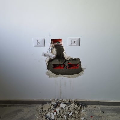 קיר עם חור, שקעים חשמליים וחוטים חשופים