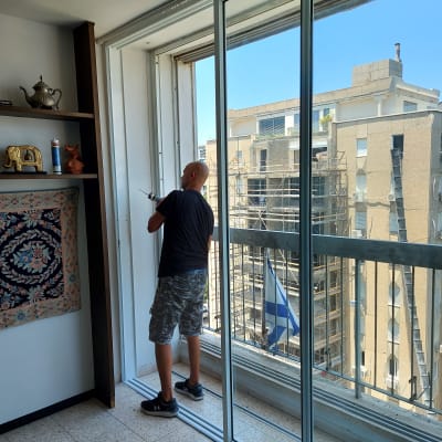אדם עובד על מסגרת אלומיניום של חלון הזזה