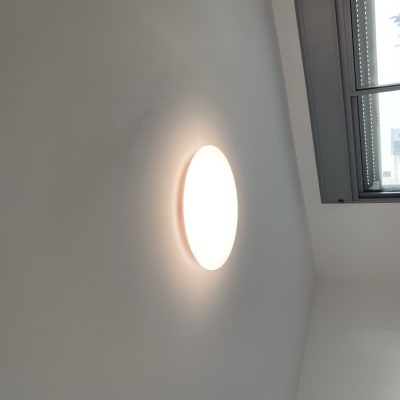 מנורת תקרה עגולה דולקת על קיר לבן