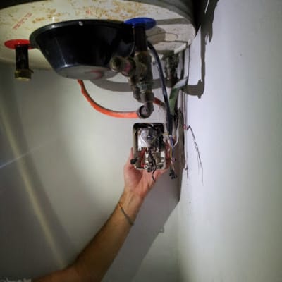 חשמלאי עובד על חיבורי חשמל בדוד מים