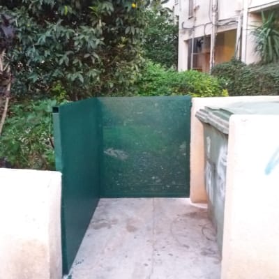 קיר מתכת ירוק ליד פח אשפה