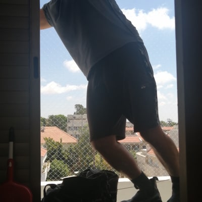 אדם מתקין רשת על חלון למניעת כניסת יונים