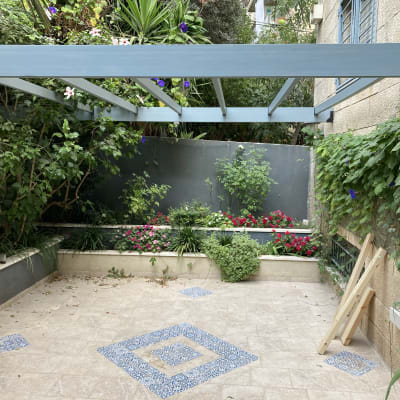 פרגולה מעץ בגינה עם צמחים ופרחים מסביב