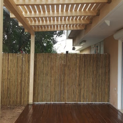 פרגולה מעץ עם רצפת דק וגדר במבוק