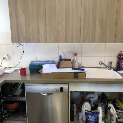 כיור מטבח עם כלים וחומרי ניקוי על השיש