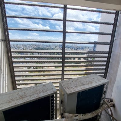 רשת מתכת על חלון עם שני מזגנים מלוכלכים